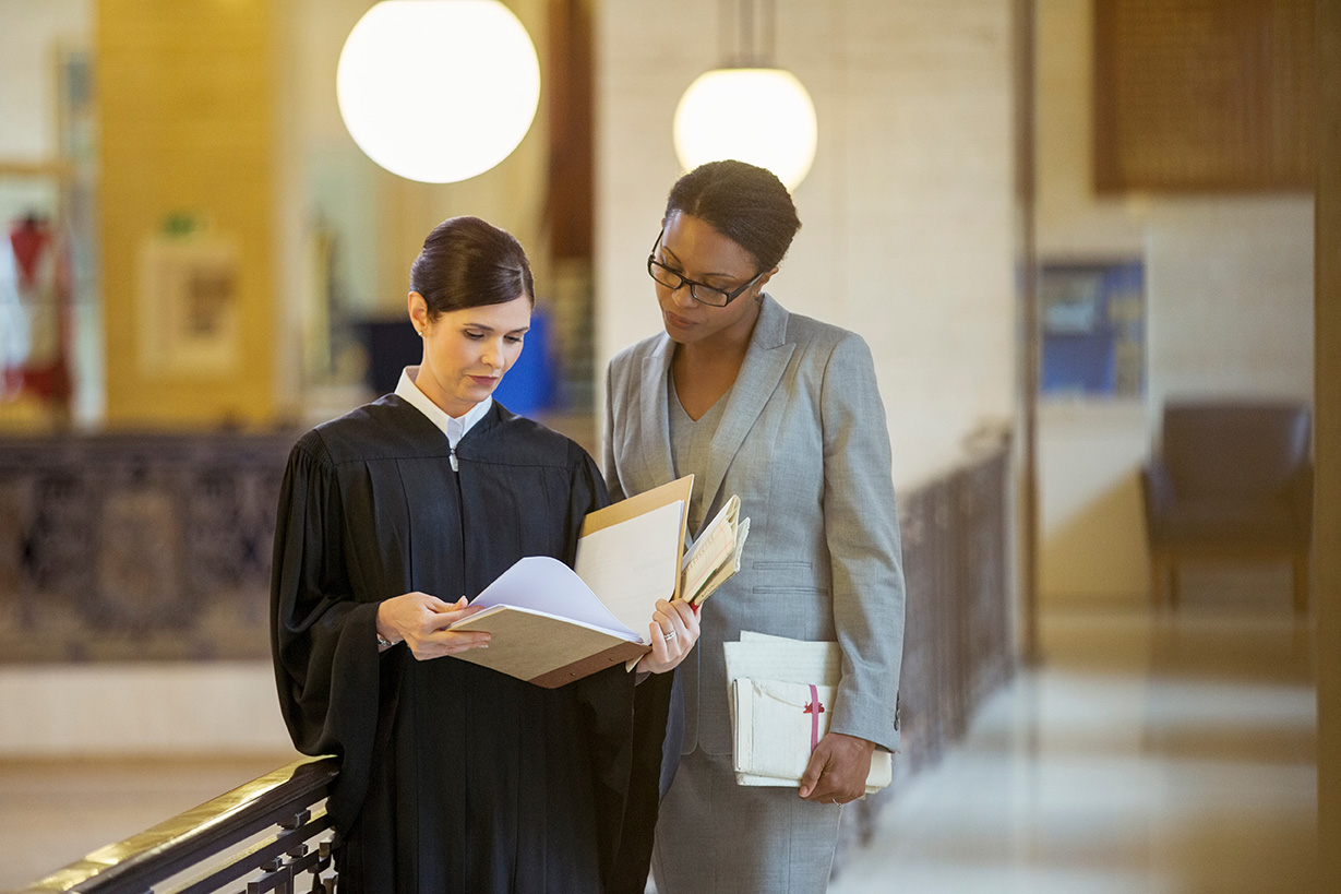 A judge and a lawyer look at legal texts together.