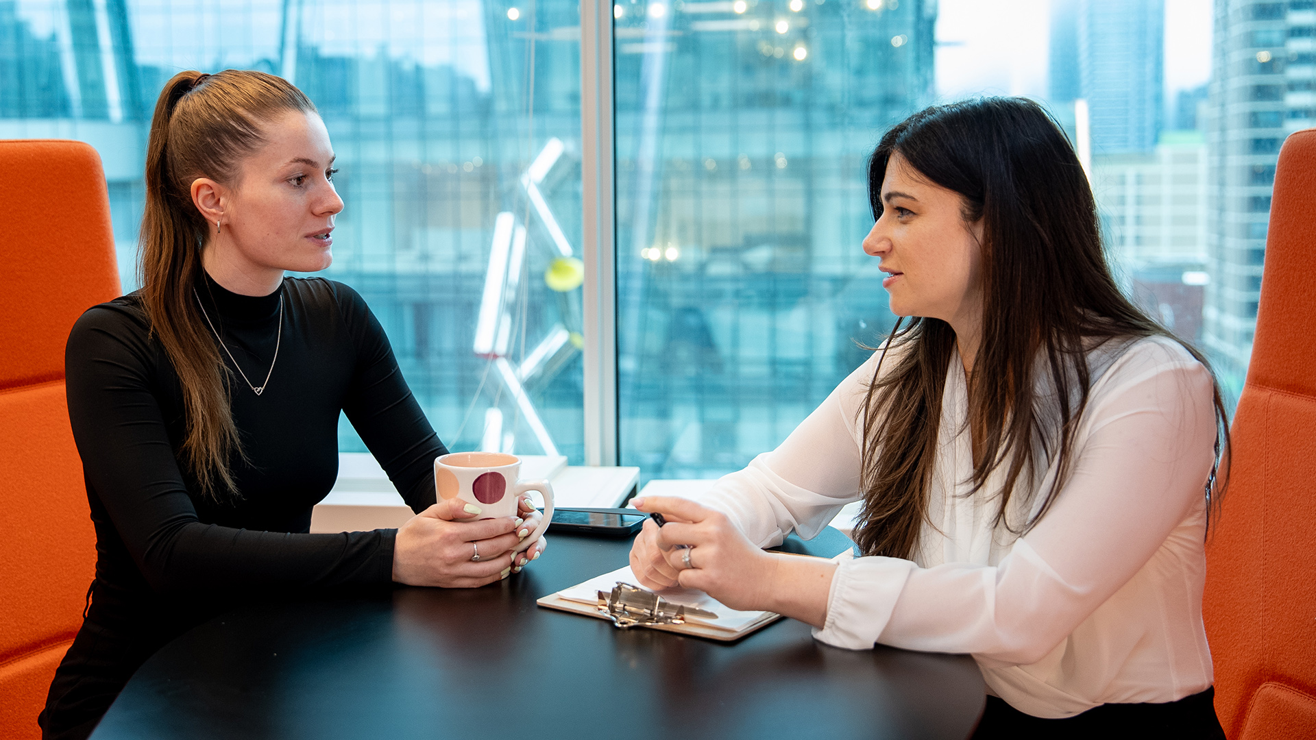 Two IPC staff members having a conversation over coffee.