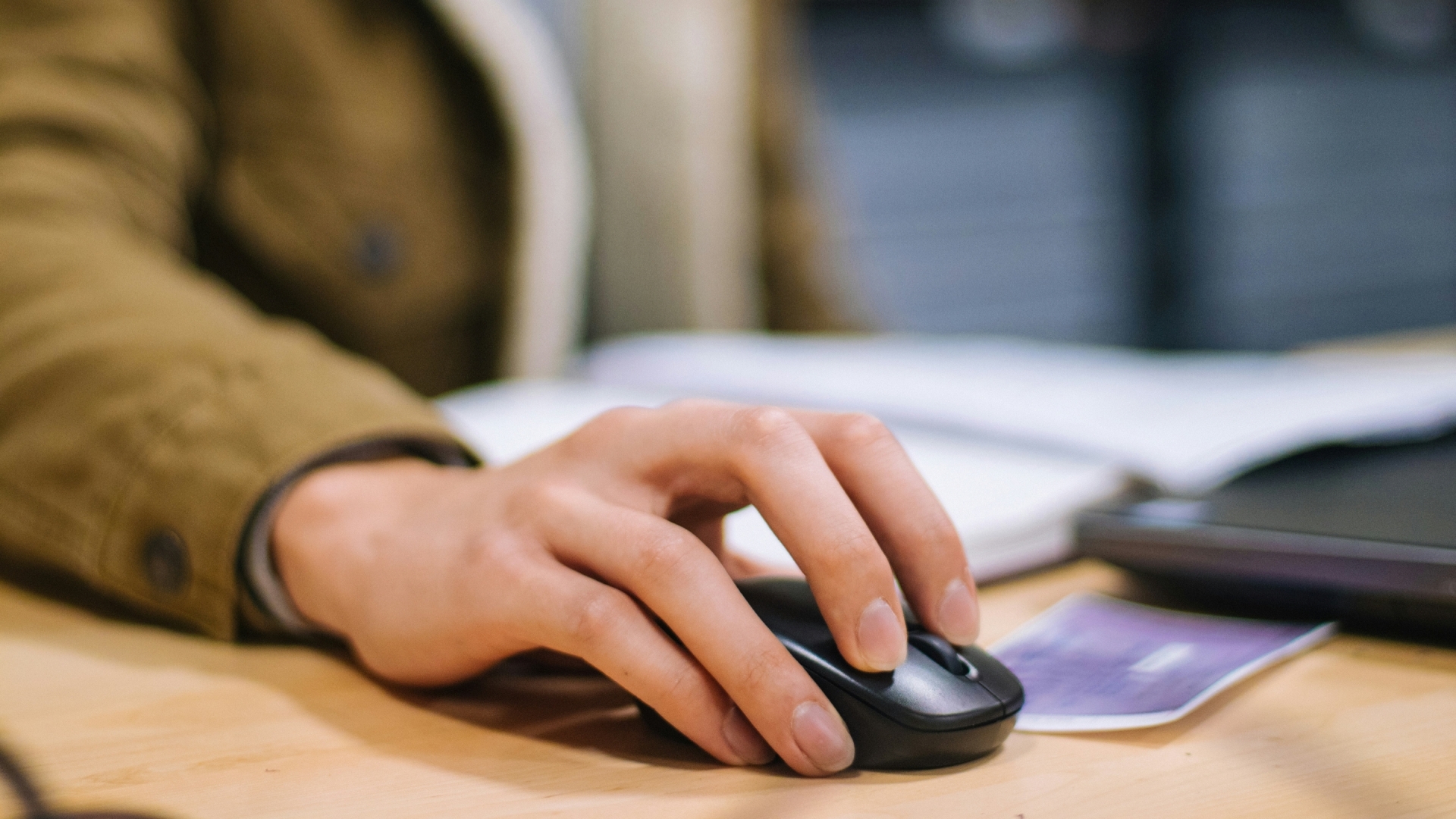 Student working at computer focused on hand using mouse.
