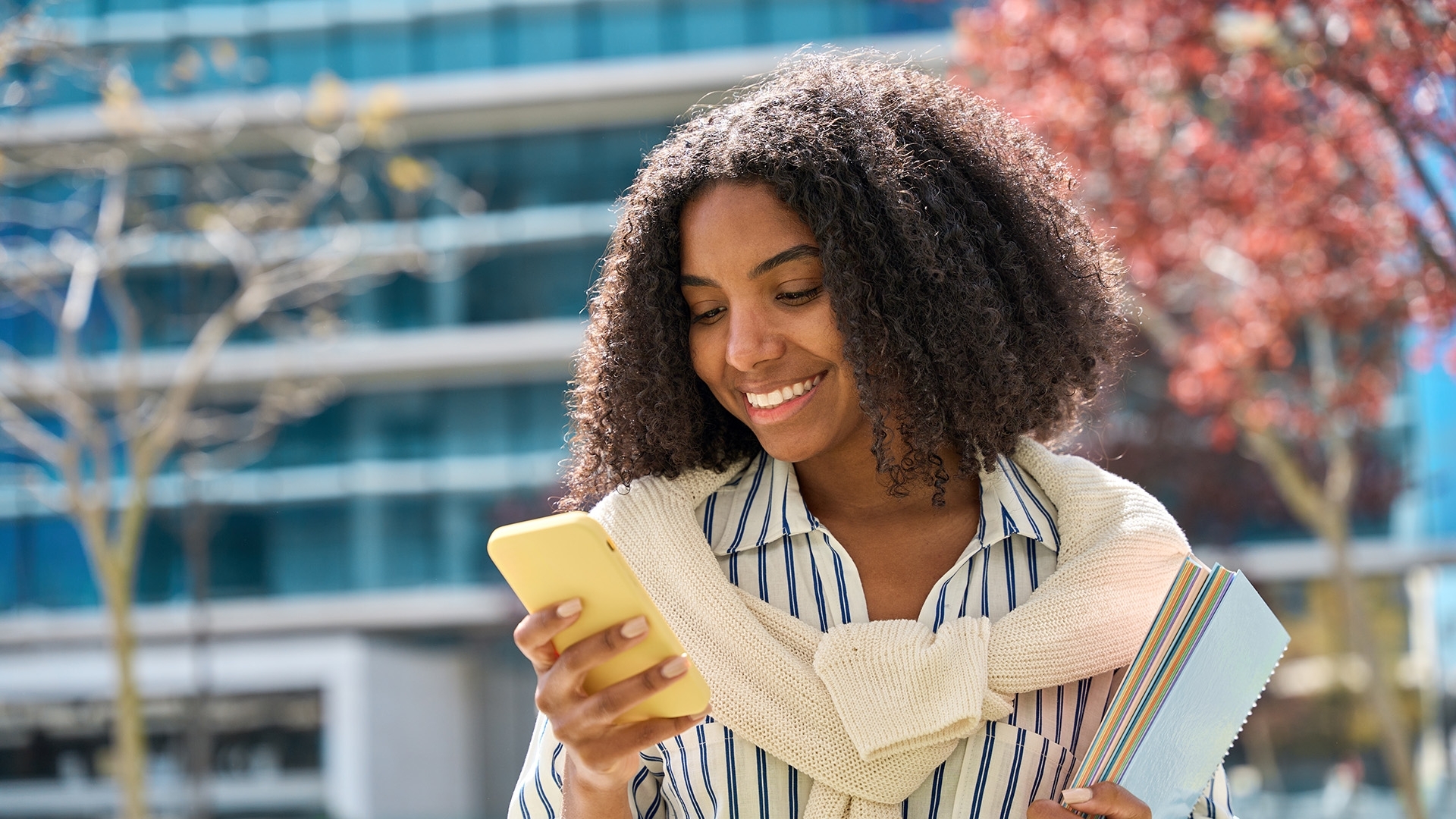 A woman smiling as she looks at a smartphone.