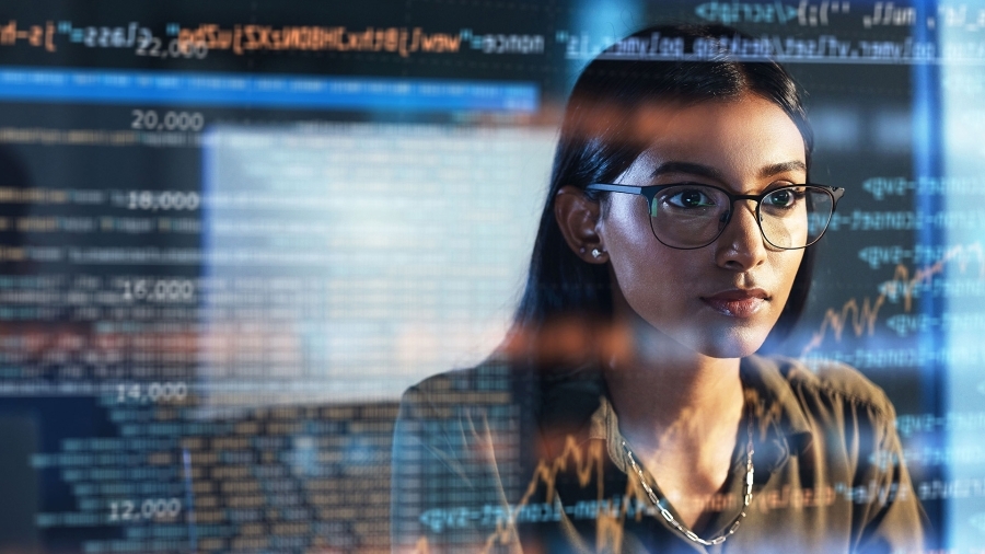 Une femme regarde un écran d’ordinateur sur lequel figurent de nombreuses lignes de code.