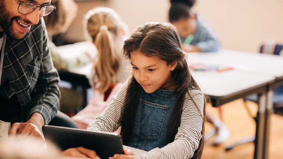 A teacher helping a student using an iPad.