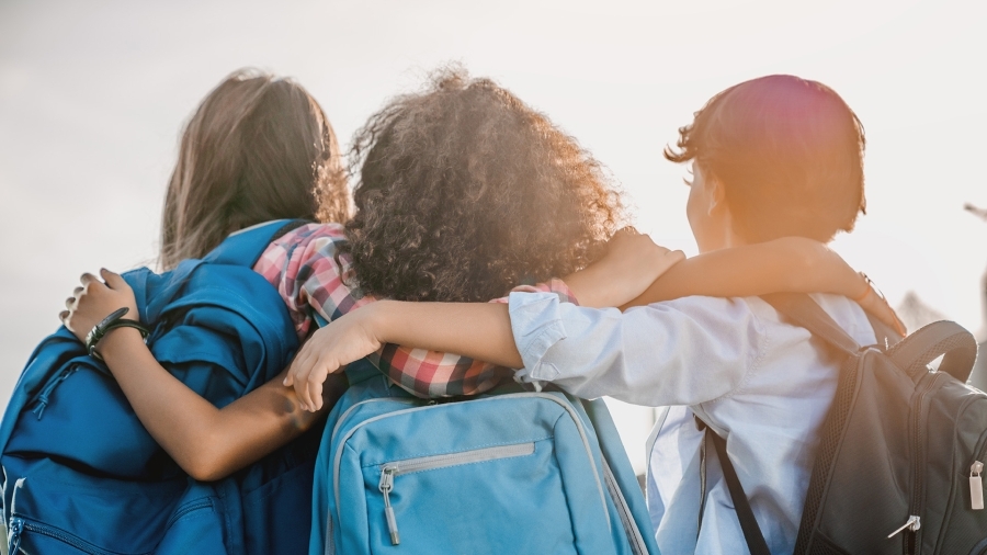 Three children with their arms over each other's shoulders.