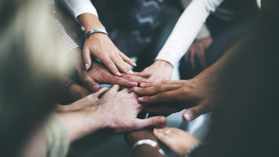A team of people huddling and putting their hands together.