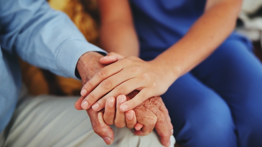 Somebody holding an older adult's hands comfortingly.