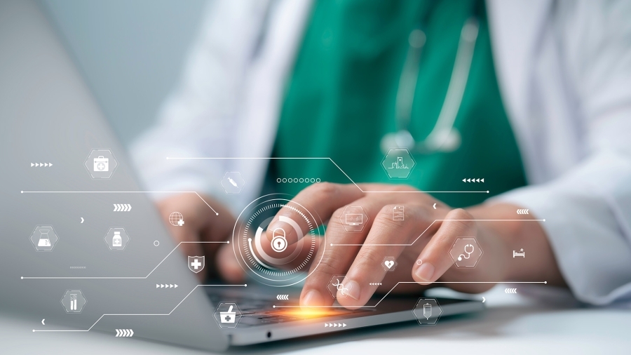 A healthcare professional typing on a laptop.