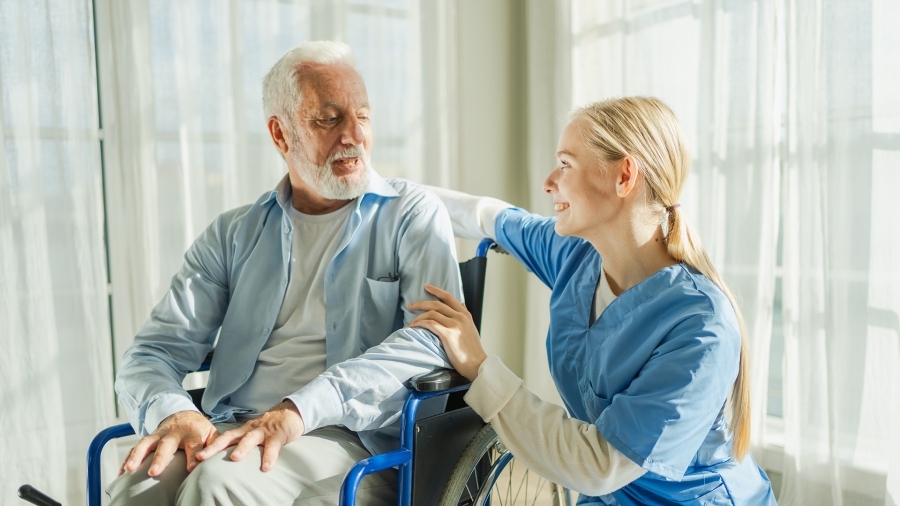Une infirmière sourit à un patient âgé.