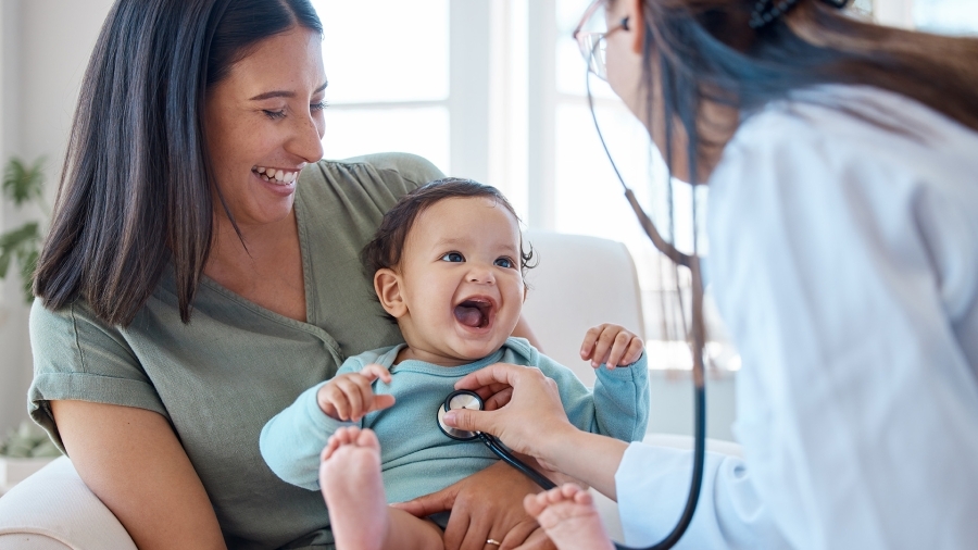 A baby laughing while a doctor listens to her heart.