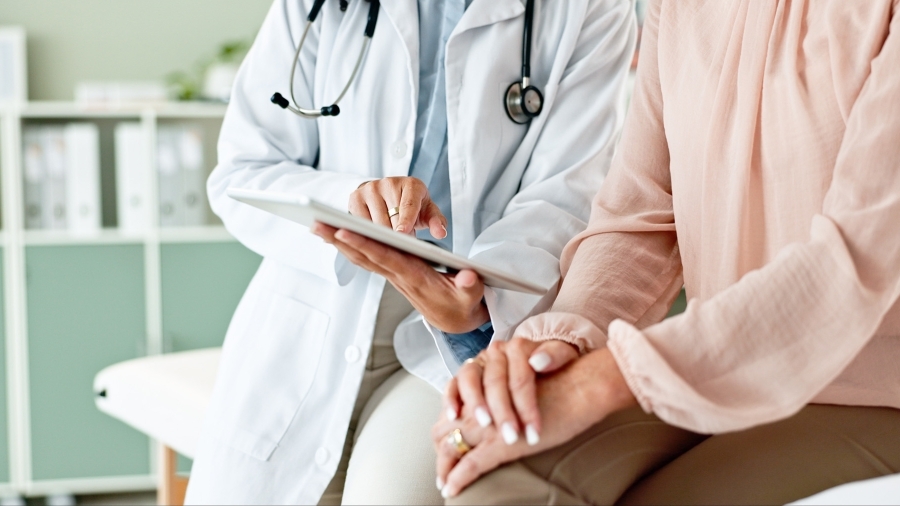 Un médecin utilise une tablette tout en parlant à un patient.