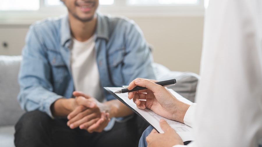 A doctor taking notes while talking to a patient.