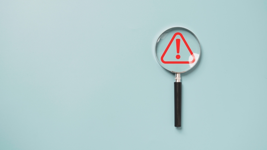 A magnifying glass hovering over a red warning icon.