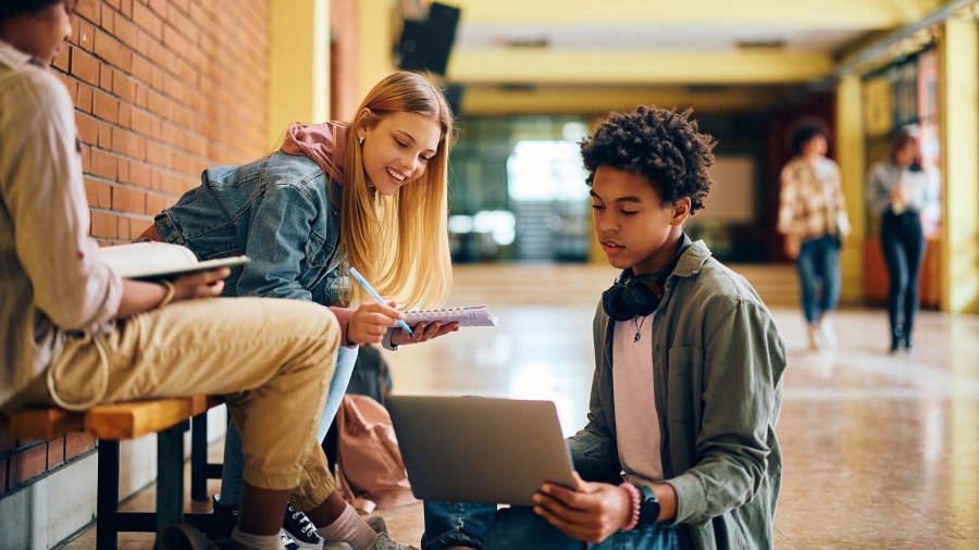 Des lycéens utilisant un ordinateur dans un couloir d'école.