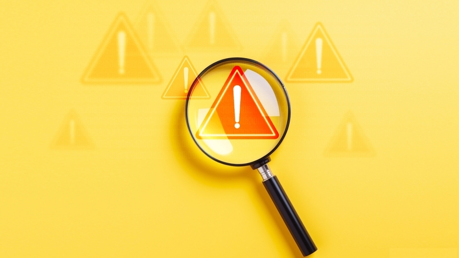 A magnifying glass hovering over a red warning icon.