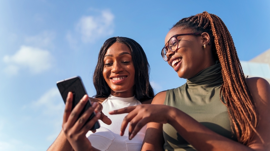 Two teenage girls looking at a phone and laughing.