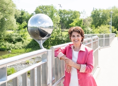 La commissaire à l'information et à la protection de la vie privée, Patricia Kosseim, pose pour une photo sur un pont, avec des arbres en arrière-plan.