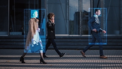 People walking down a city street as a surveillance camera tracks them.