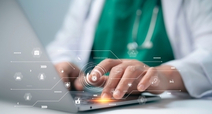 A healthcare professional typing on a laptop.