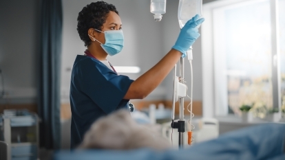 A nurse adjusting a patient's IV bags.