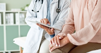Un médecin utilise une tablette tout en parlant à un patient.