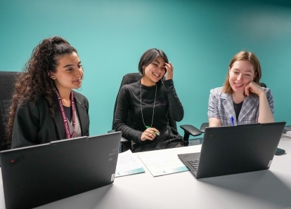 Three of the IPC's summer students sitting at a desk.