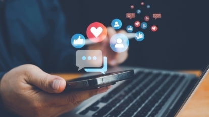 Somebody using a smartphone, with social media icons floating around it.